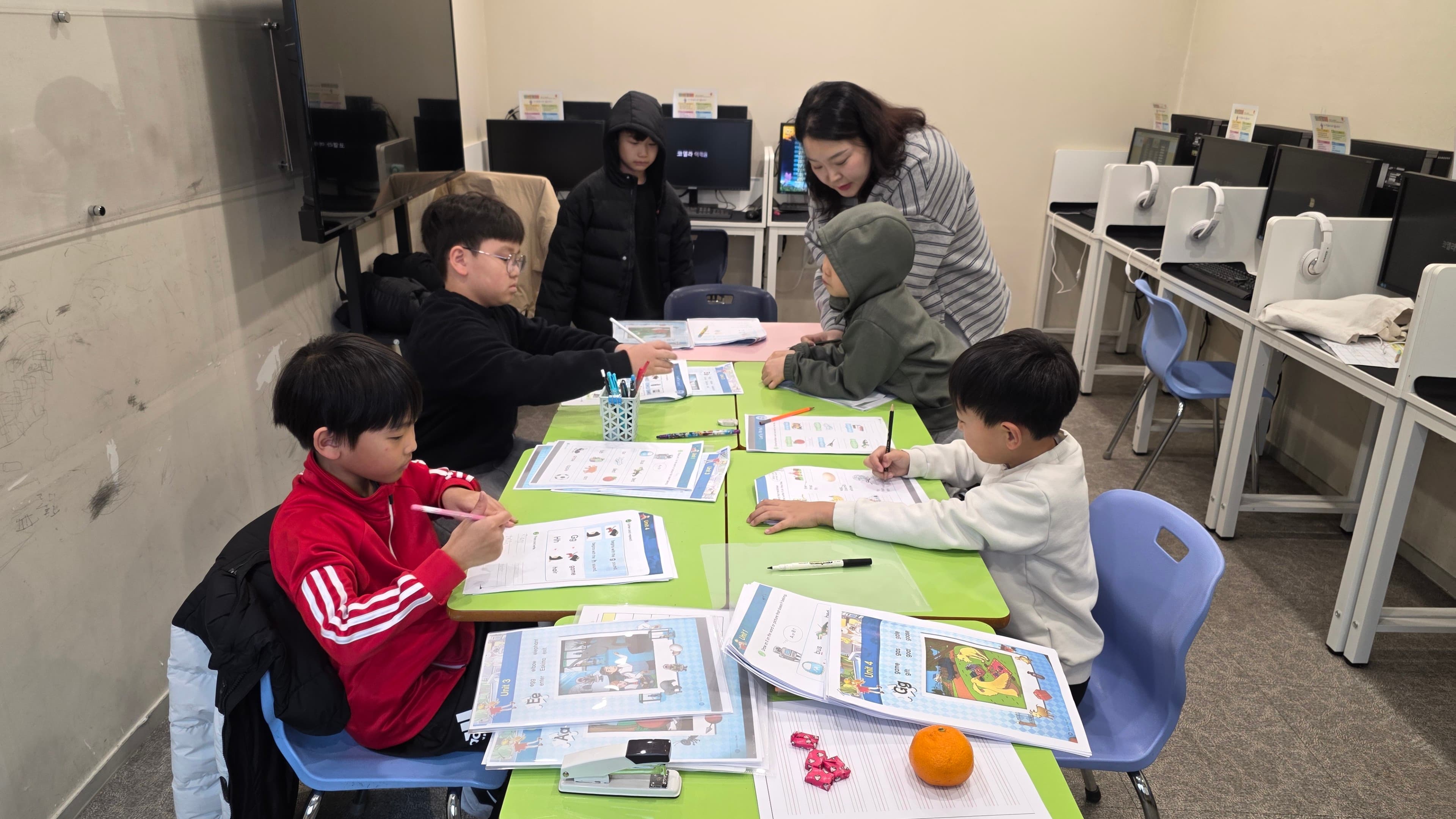 선생님이 파닉스 교재로 1:1 지도하는 모습